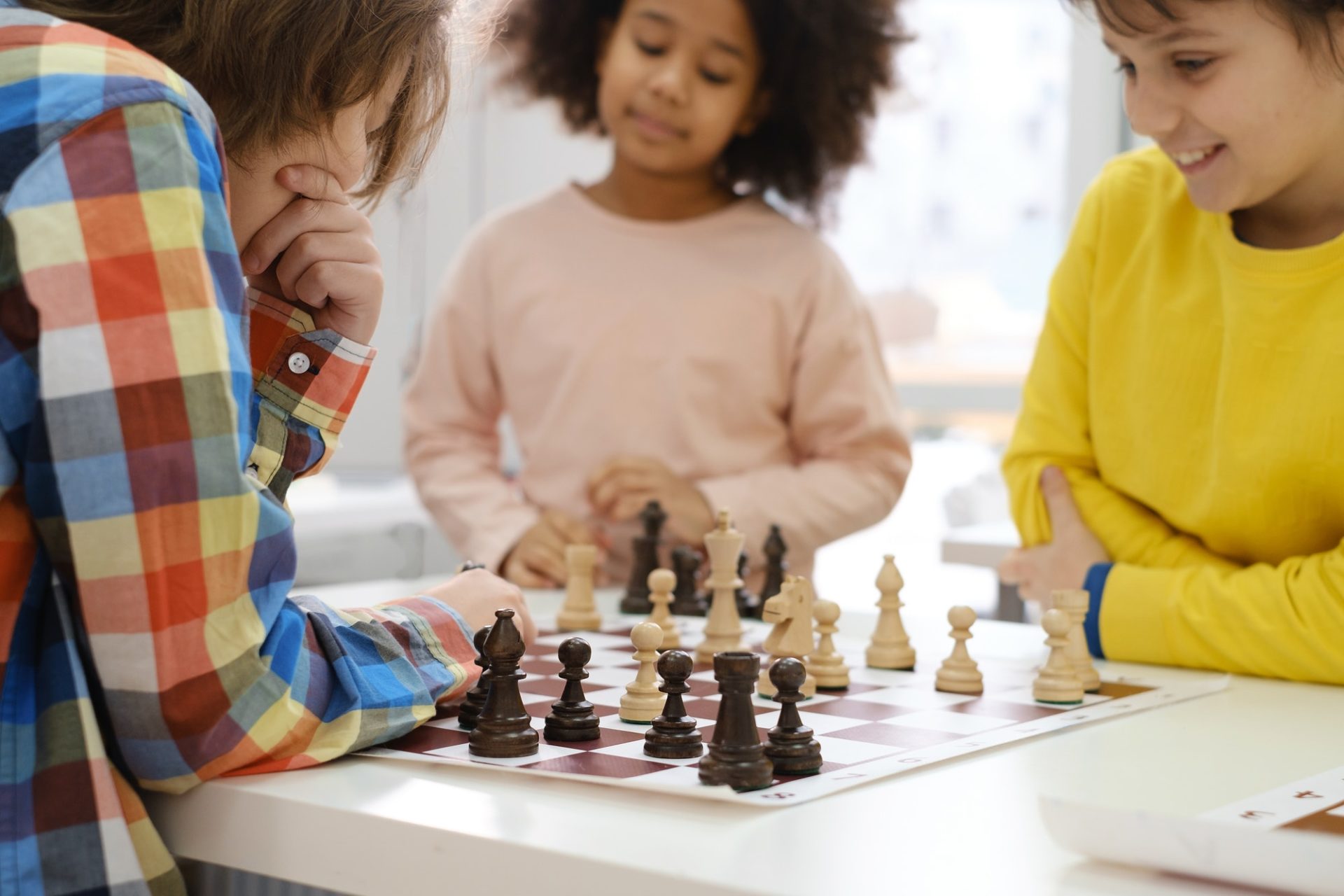 multiethnic-kids-playing-chess-board-game-at-school